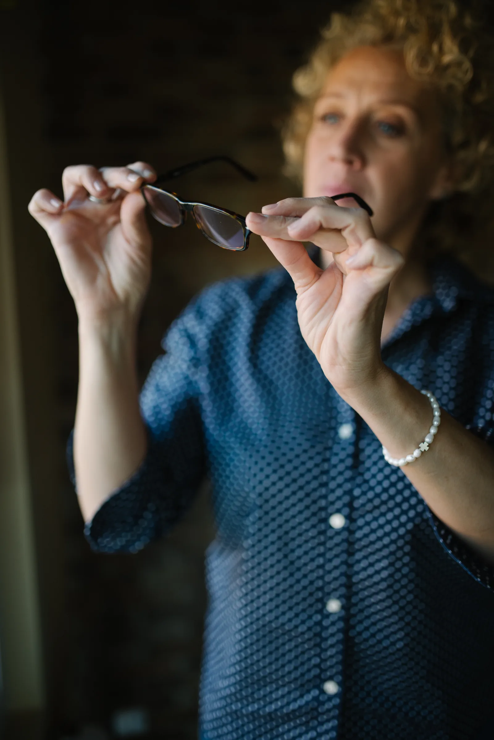 A beautiful woman with curly hair holding a sample of glasses closeup