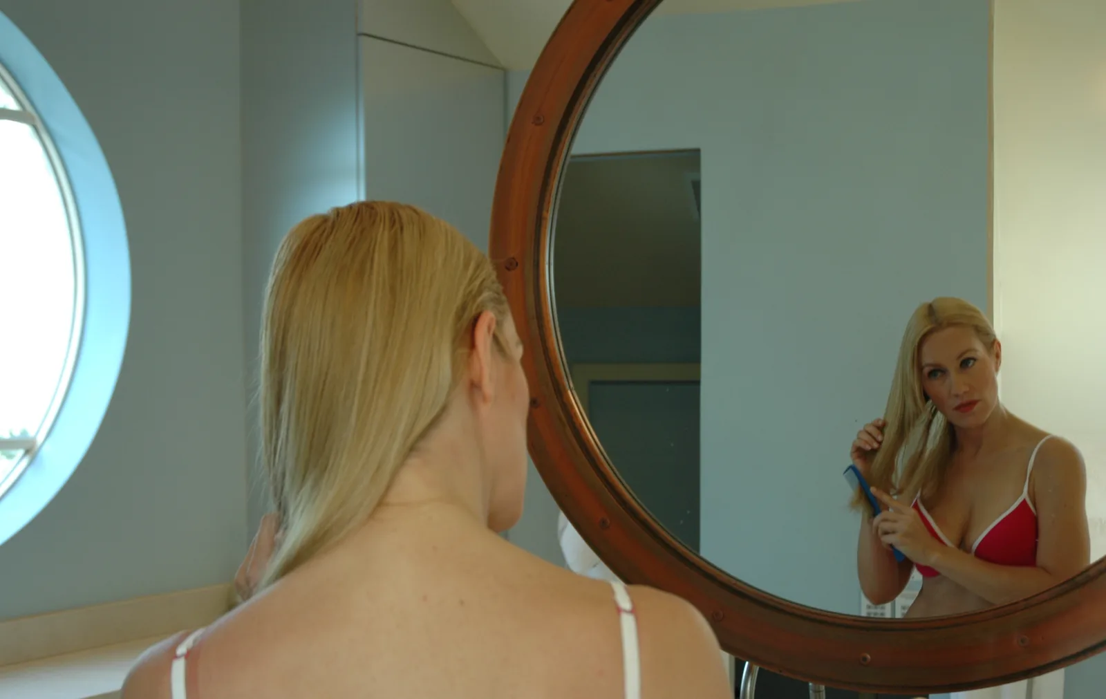 Blond woman combing her hair in mirror