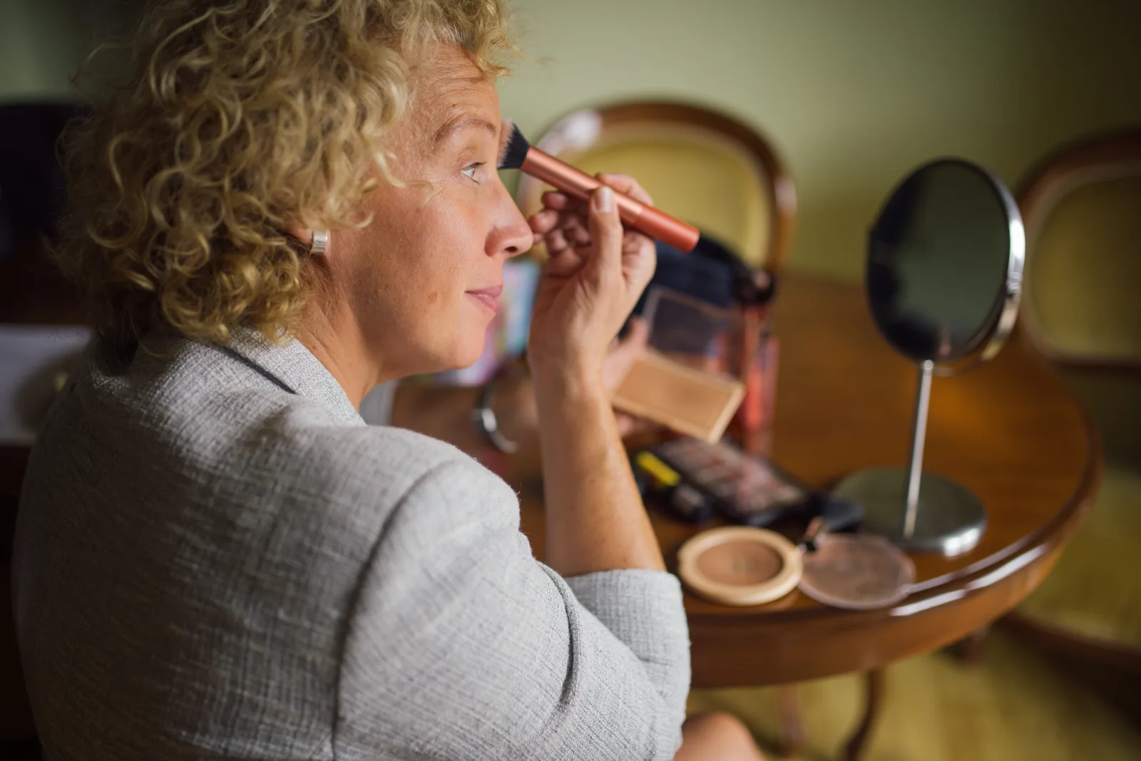 Close-up of a woman applying makeup in front of a mirror