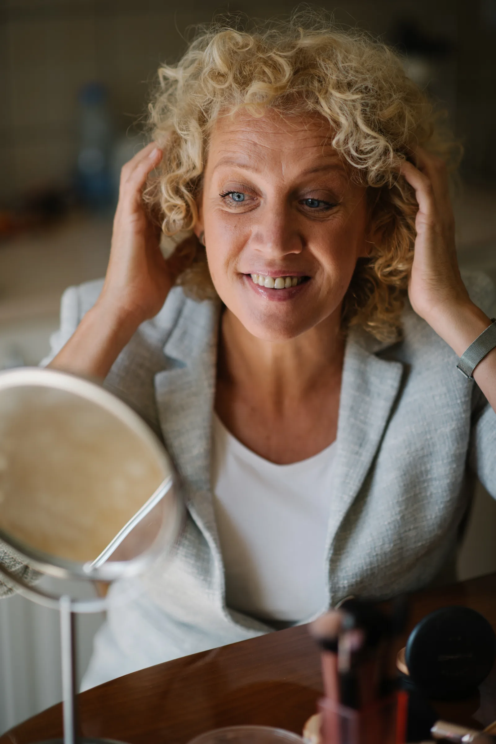 Close-up of a woman with blonde curly hair looking at the mirror and smiling