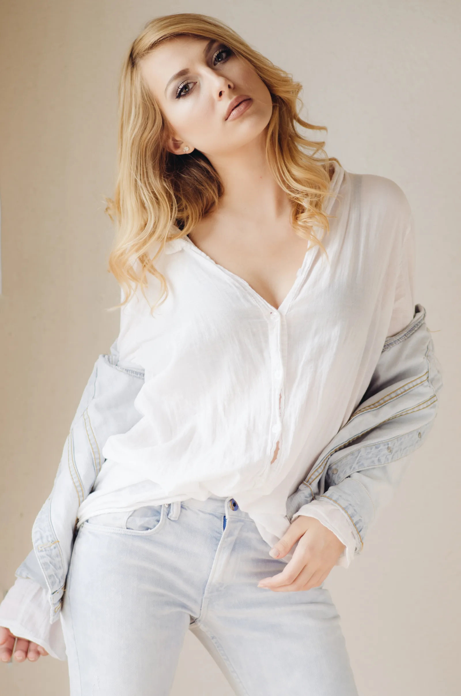 Portrait of young blonde beautiful woman standing near window