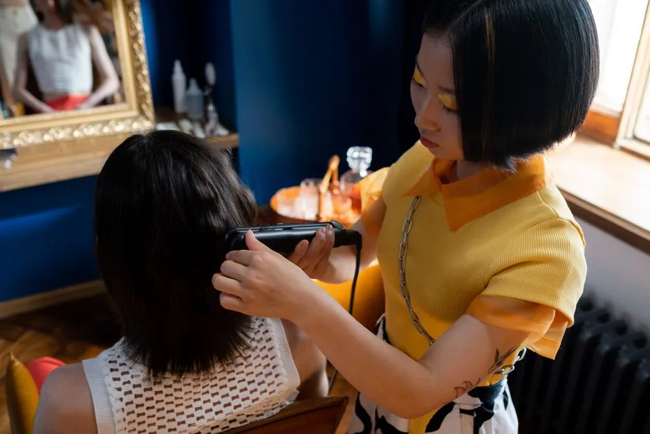 A hairdresser styles a client's hair with a straightener in a modern salon setting.