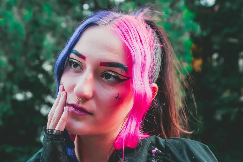 Young woman with vibrant colored hair and artistic makeup posing outdoors.