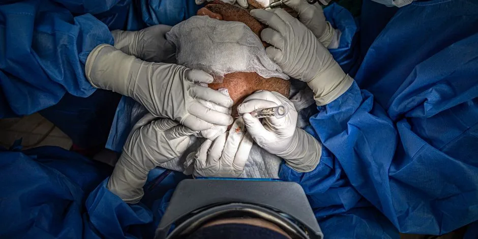 Surgeons in an operating room performing a precise medical procedure under sterile conditions.