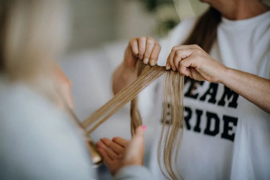 Bride's hair being styled, emphasizing a close-up of hands and long hair strands in preparation for a wedding.