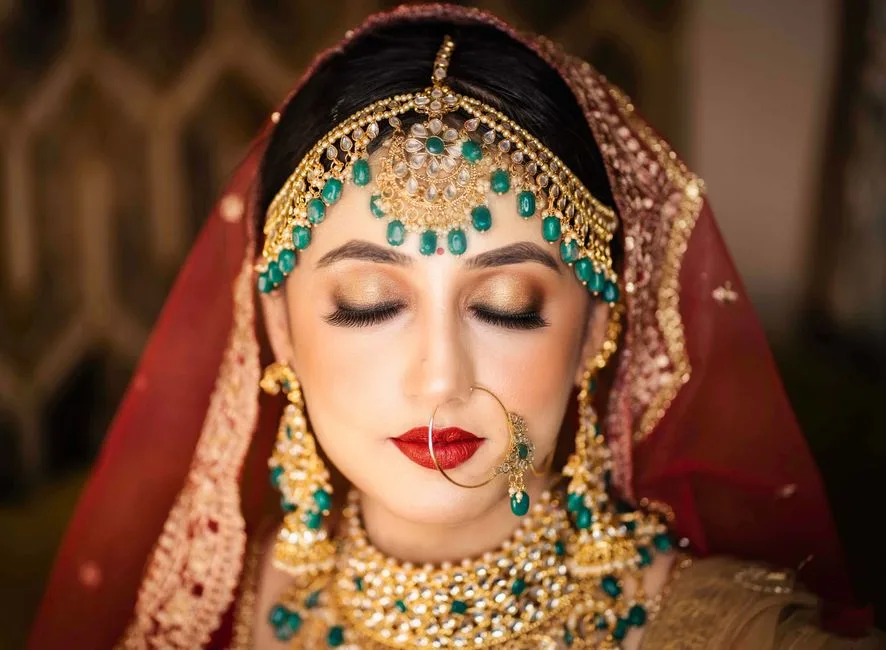 Close-up of an Indian bride in traditional jewelry and makeup with eyes closed, exuding elegance.