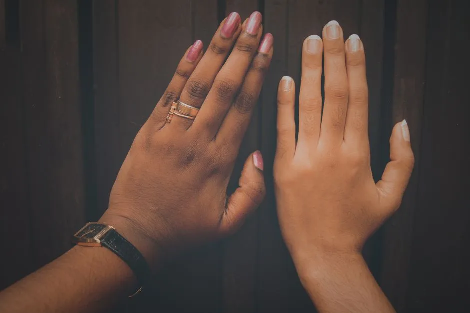 Close-up of two manicured hands with rings showcasing diversity and fashion.