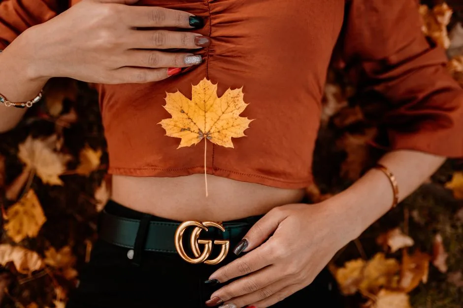 Close-up of a woman's autumn outfit with a maple leaf, highlighting fall fashion and seasonal vibes.