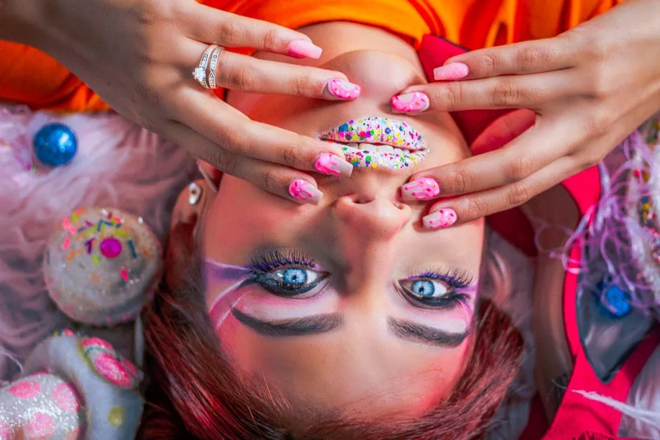 Colorful portrait of a woman with artistic makeup and nail art. Bright and creative fashion style.