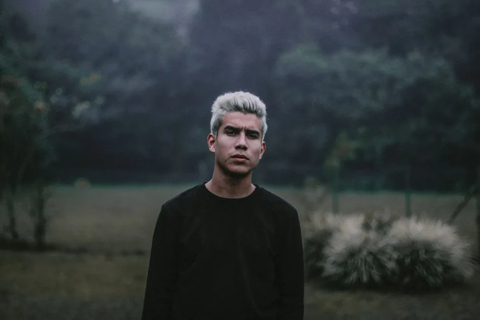 A young man with blonde hair standing in a foggy forest in Chiriquí, Panama.