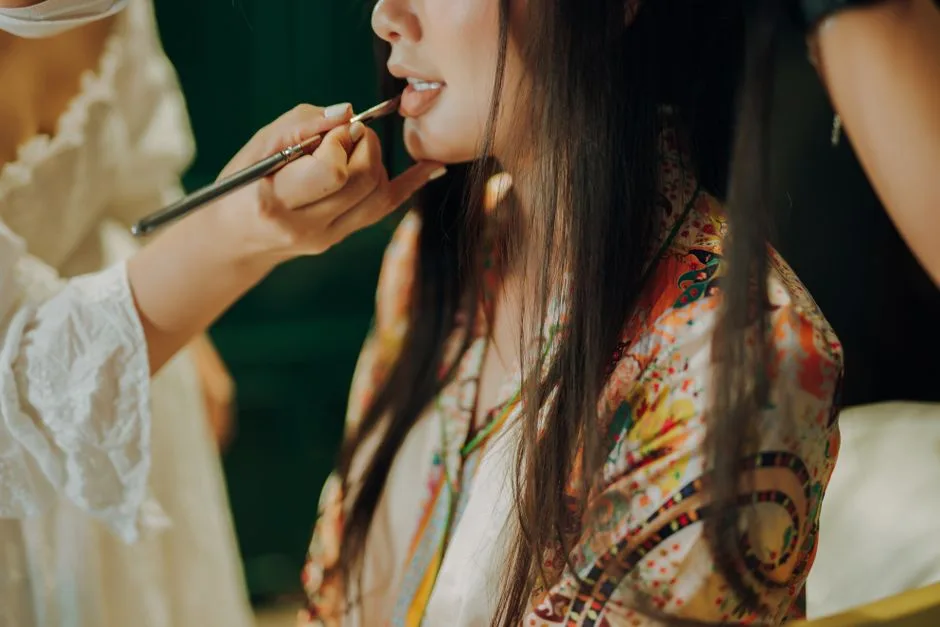 Close-up of a woman receiving a detailed lipstick application before an event.