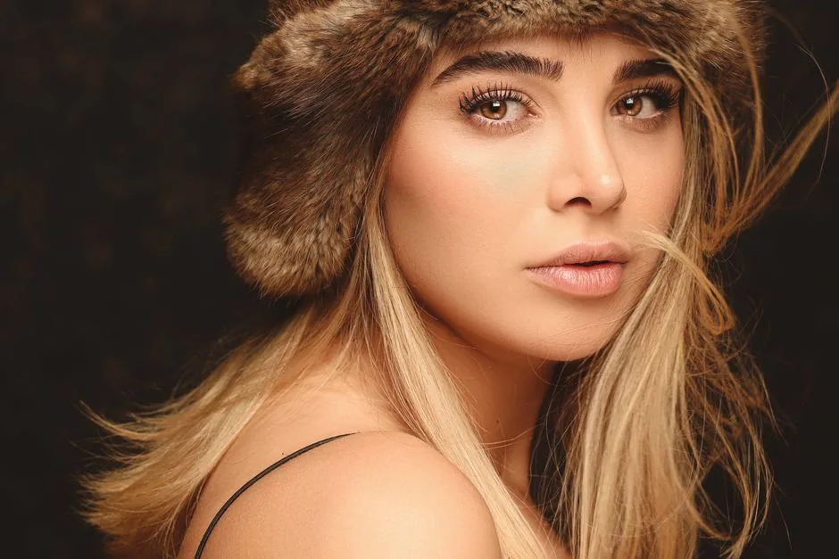 Close-up portrait of a blonde woman wearing a fur hat, exuding glamour and beauty.