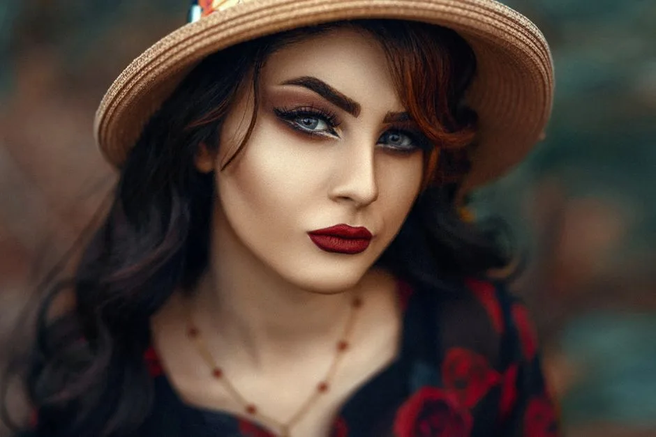 Close-up portrait of a woman with elegant makeup and a hat, showcasing beauty and style.