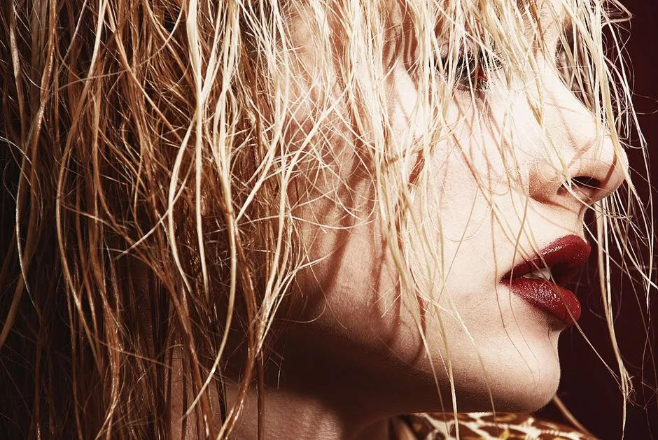 Artistic close-up of a woman with wet blonde hair and bold lipstick