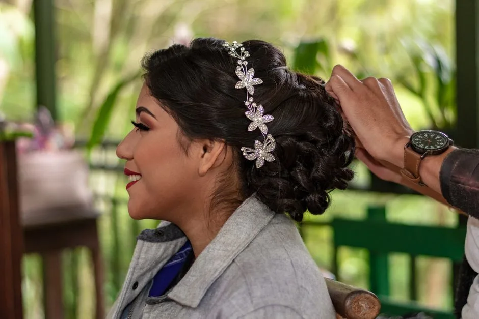 Woman having an elegant hairdo done outdoors, featuring floral hairpins.
