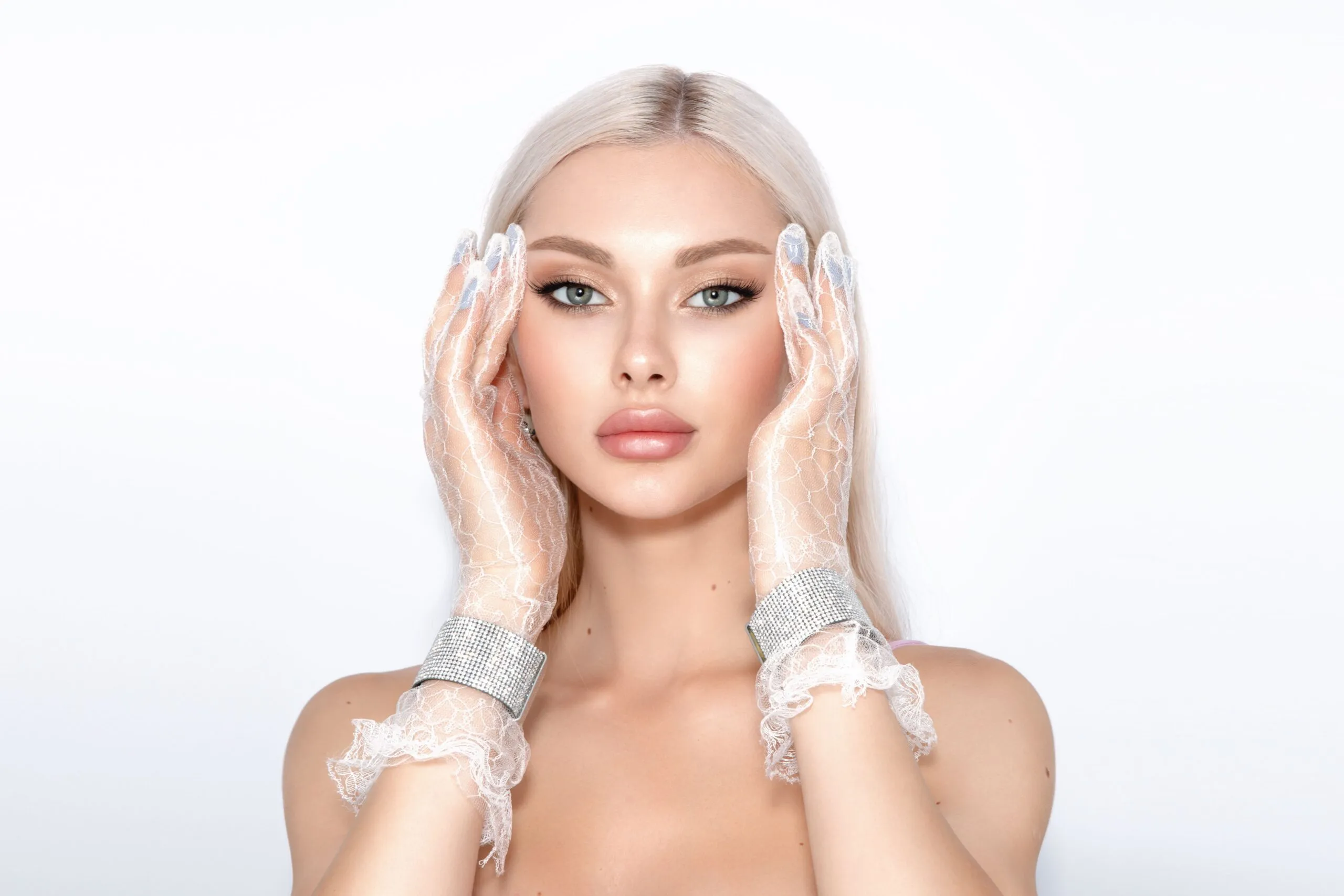 Elegant portrait of a blonde woman in lace gloves against a white background, showcasing glamour and style