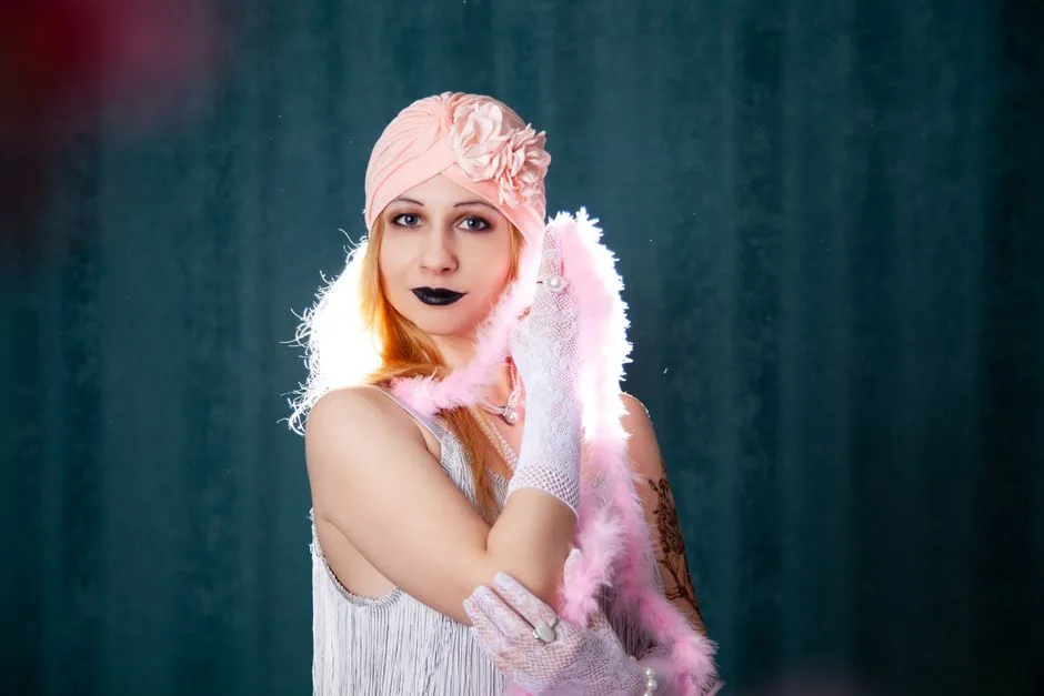 Elegant woman in vintage 1920s attire with a feather boa and floral headpiece.