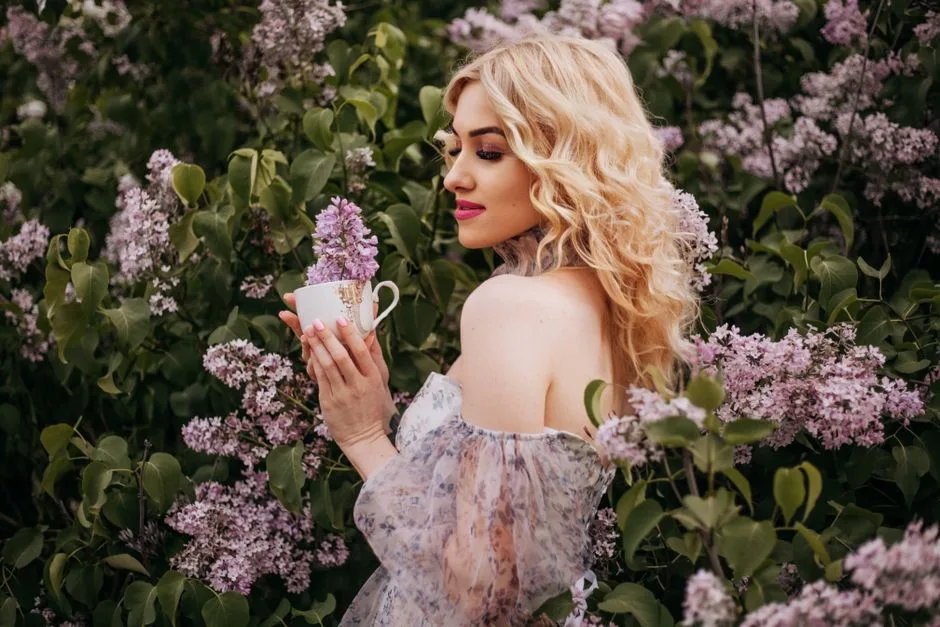 Elegant portrait of a woman in a floral scene holding lilacs, capturing spring beauty.