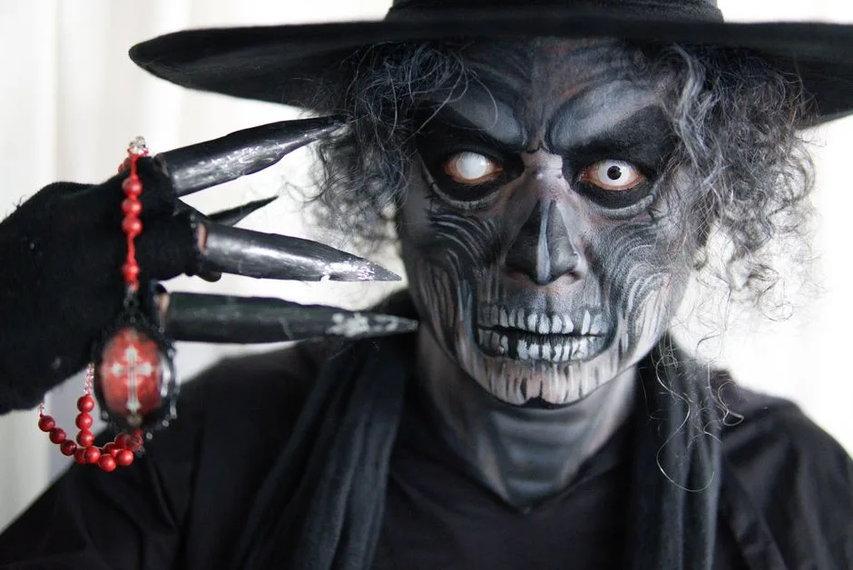 Close-up of a person in skeleton makeup and costume, holding beads with claws.
