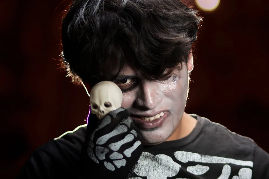 A person in skeleton makeup holding a small skull, perfect for Halloween themes.