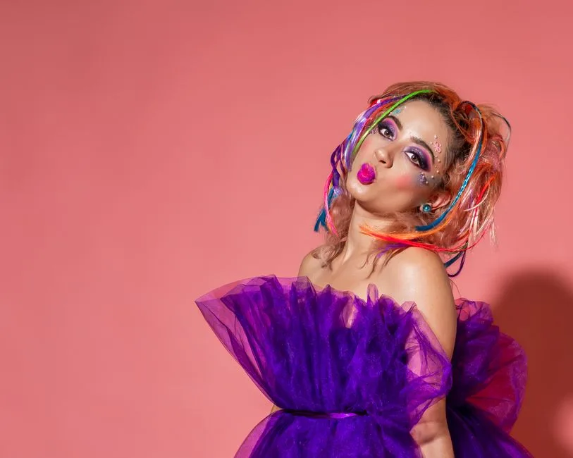 Colorful artistic portrait featuring a woman with creative makeup and vibrant attire.