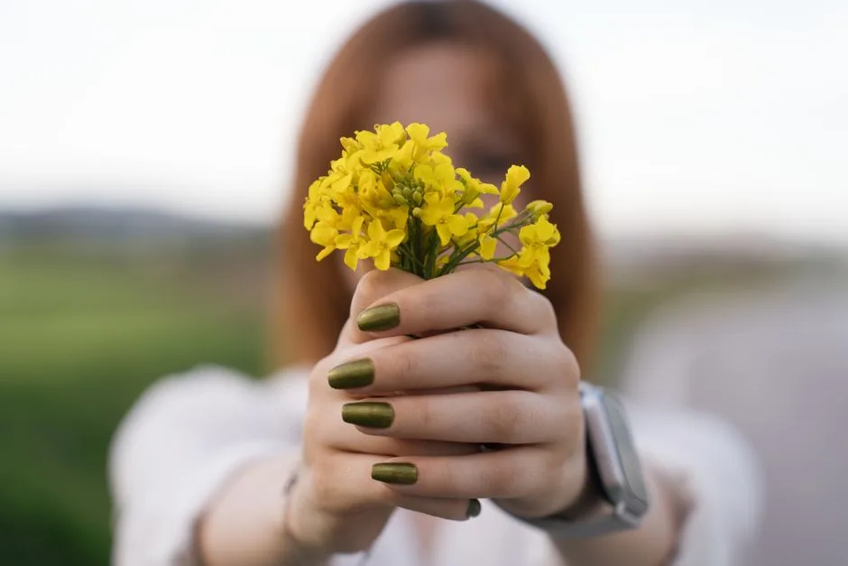 Close-up of a woman holding yellow flowers with green nails in Merzifon, Türkiye.