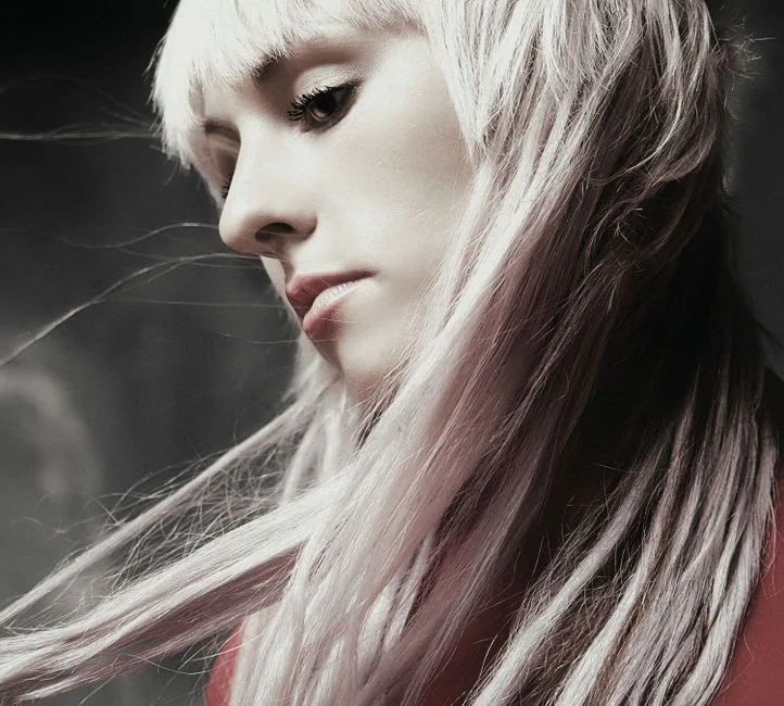 Artistic portrait of a woman with flowing platinum hair and soft lighting.