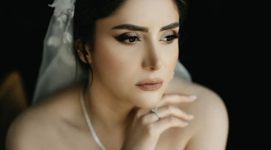 Close-up portrait of a thoughtful bride with elegant makeup and a white veil.