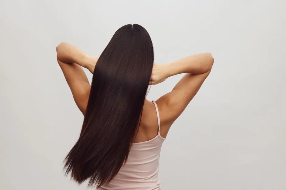 Asian woman with long, straight hair shown from behind, embracing hair care and beauty.