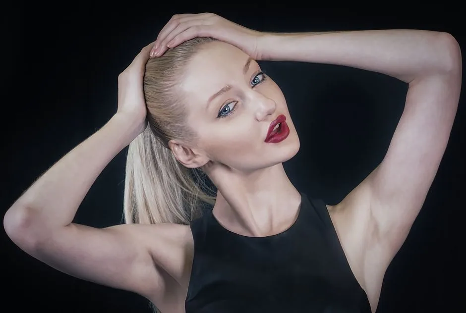 Close-up portrait of a stylish woman with red lips and a sleek ponytail, striking a pose.