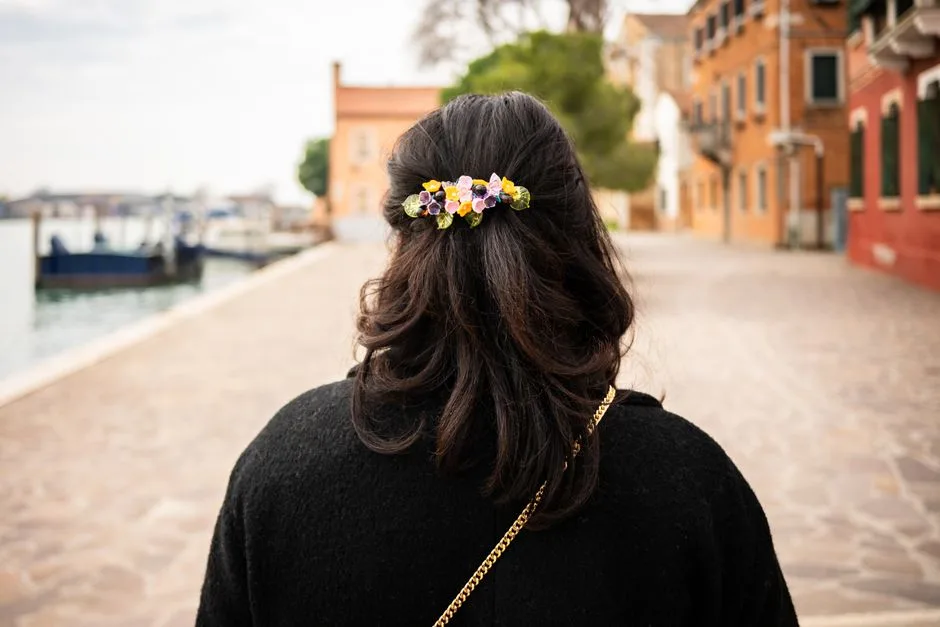 Rear view of a woman with floral hair accessory walking along a canal in Venice.
