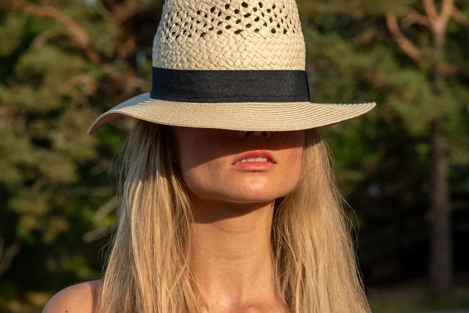 Elegant woman with blonde hair wearing a stylish straw hat outdoors in Helsinki, Finland.