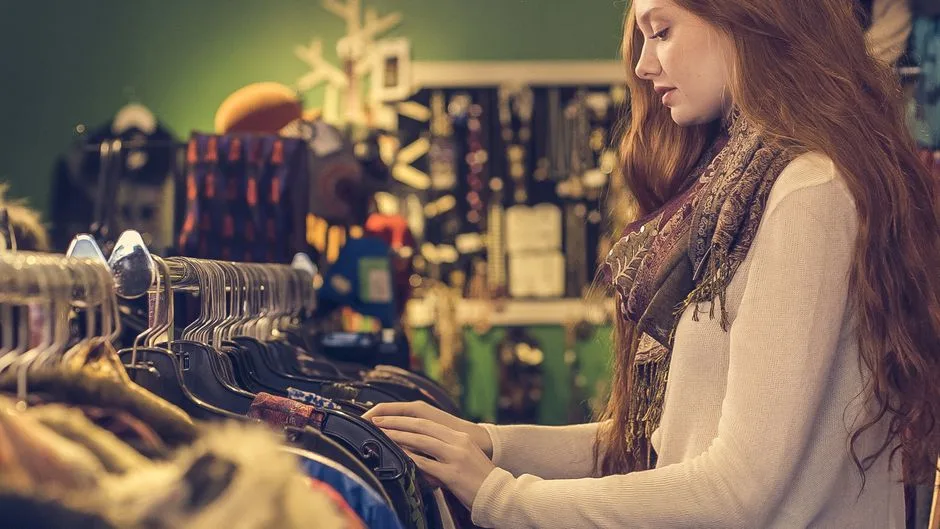 A young woman shops for fashion clothing in a vintage-themed store.