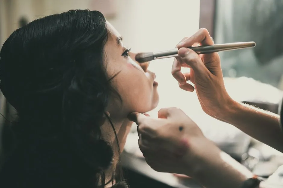 Close-up of an Asian woman getting her makeup done by a professional, emphasizing beauty and care.