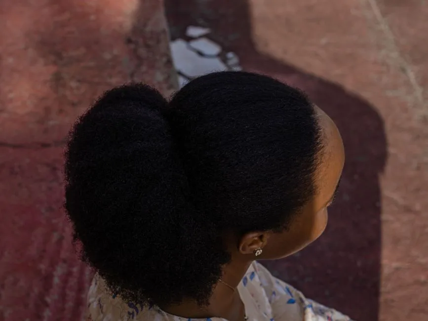 Overhead shot of a woman with a natural hair bun, showcasing textured hair under natural lighting.