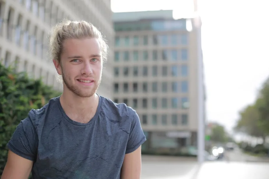 A handsome young man smiling outdoors in a city environment.