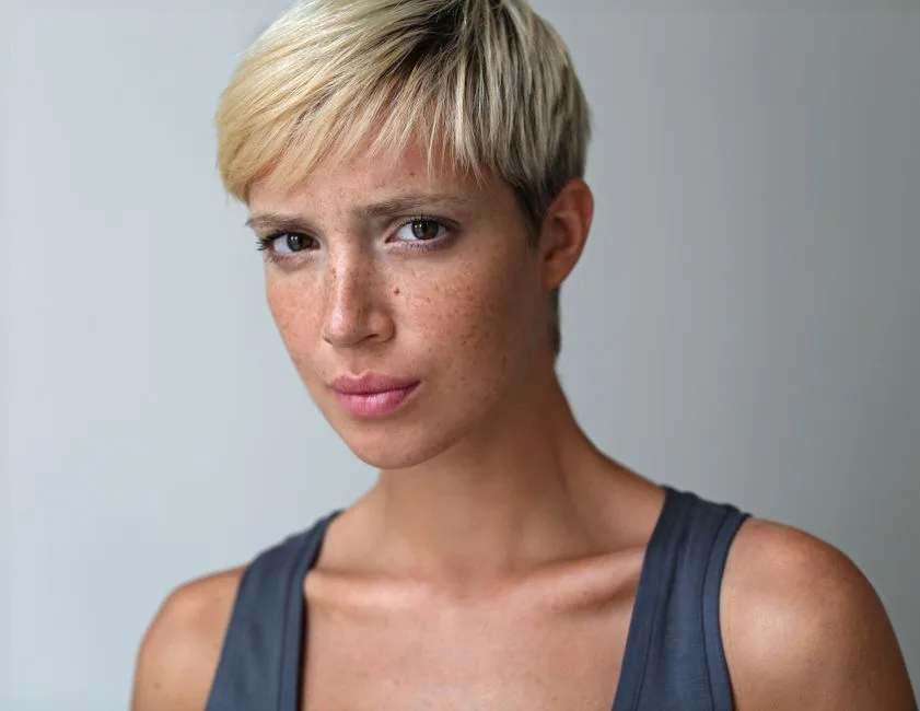 Studio portrait of a blonde woman with freckles, wearing a tank top.