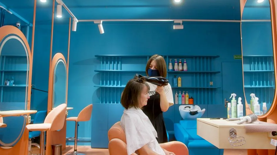 Hairstylist uses blow dryer on client in stylish, modern salon.