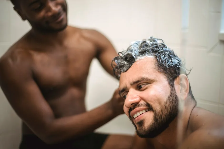 Interracial gay couple expresses love and togetherness while washing hair in the shower.