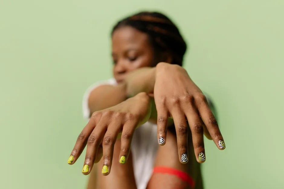 A close-up shot of a woman showcasing intricate nail art designs with a soft green backdrop.