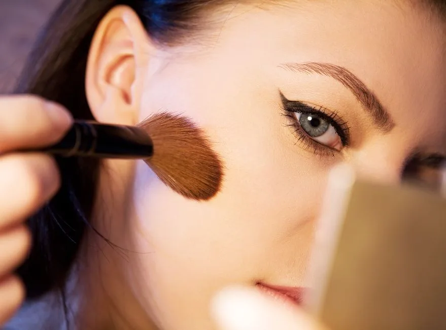 A close-up shot of a woman applying makeup with a brush.