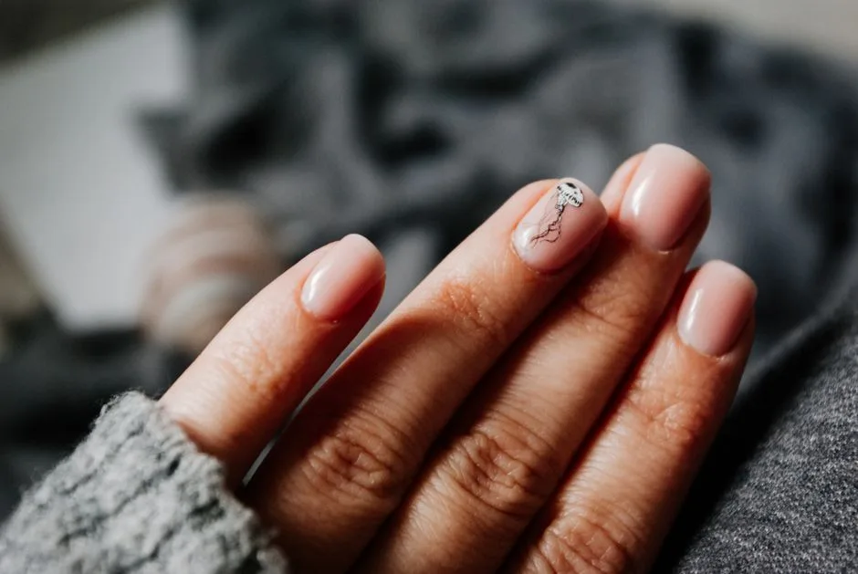 From above of crop unrecognizable female in warm sweater demonstrating hands with manicure with creative nail art