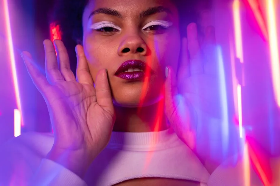 Vibrant portrait of a woman with neon lighting and bold makeup, showcasing modern artistic style.