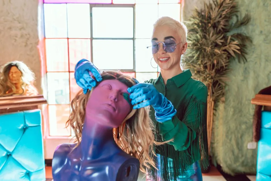 A stylist creatively working on a mannequin head with vibrant hair in a salon.