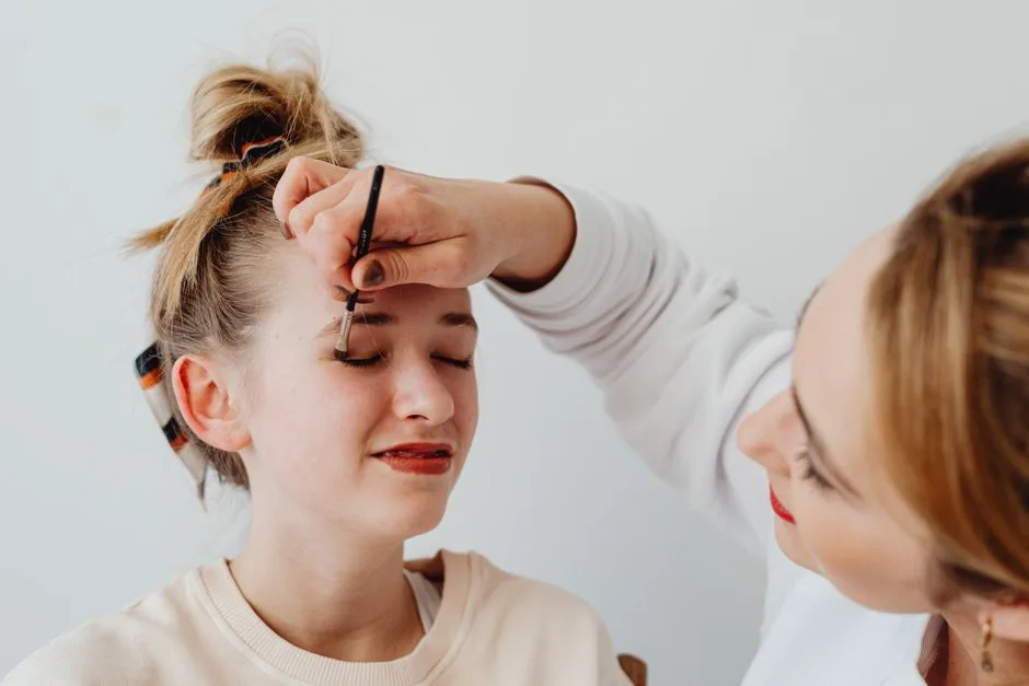 Two women engaged in a makeup application session with focus on eyeshadow.