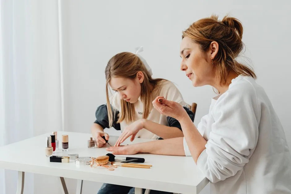 Adult woman and young girl applying nail polish in a home setting.