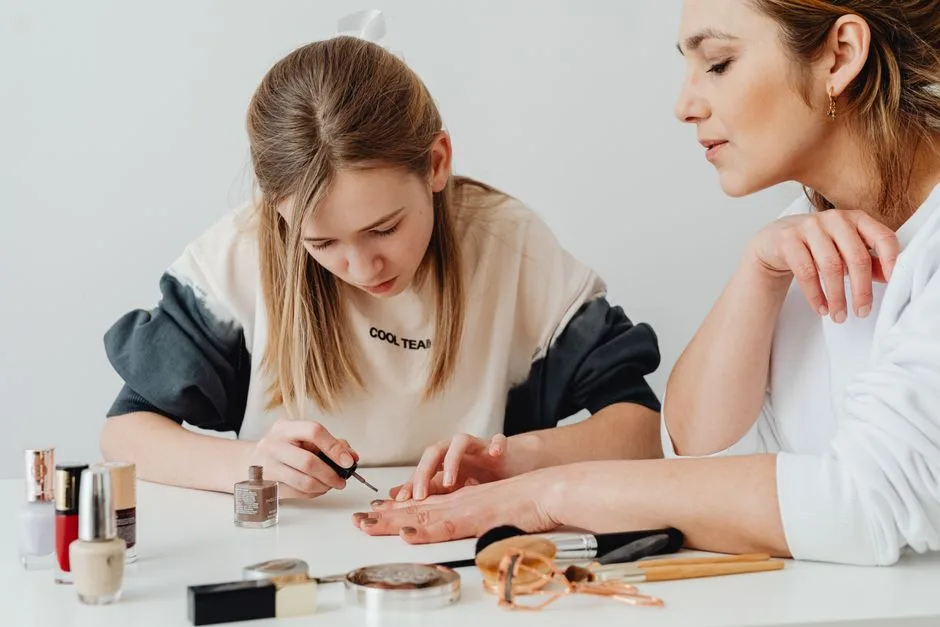A mother and daughter enjoy quality time painting nails indoors, surrounded by cosmetics.
