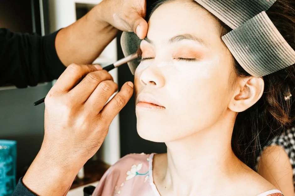 Close-up of a woman getting professional eye makeup applied by a makeup artist.