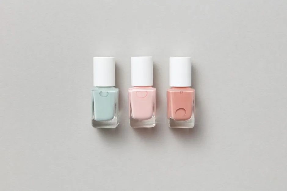 Three pastel nail polish bottles elegantly arranged on a neutral gray surface. Perfect for beauty product promotions.