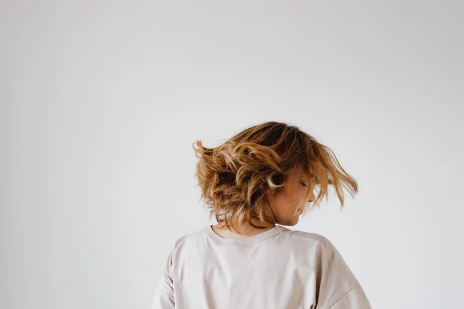 Woman performing a hair flip, showcasing dynamic motion against a minimalist white backdrop.